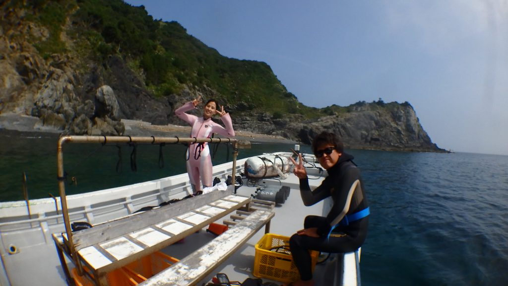 横島断層と呼ばれるダイビングポイントへ到着した後、船の上で記念撮影をします。とても楽しそうにポーズをとる二人のダイバーが写真に写っています。